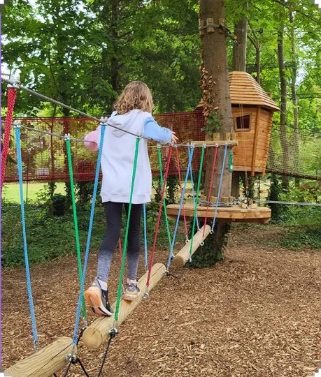 Un enfant marche sur une structure en bois en hauteur.